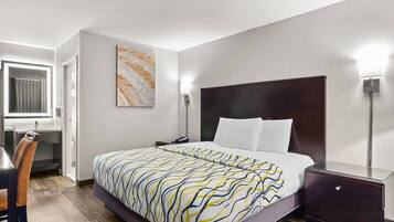 Una habitación de hotel moderna con una cama grande, una mesita de noche y un escritorio con una silla.
