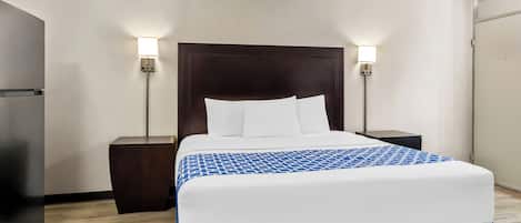 A hotel room with a large bed, two bedside tables, and a nightstand.
