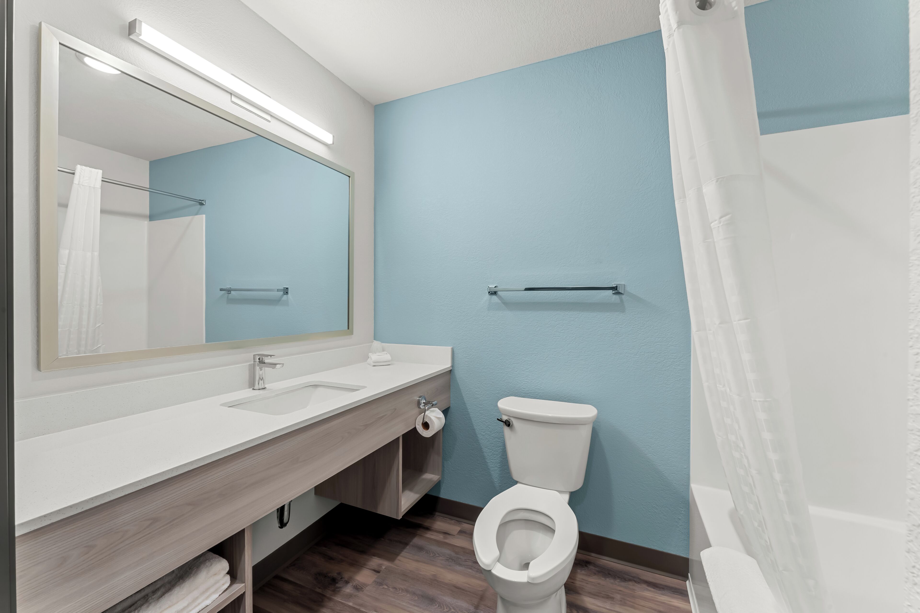 Une salle de bain avec un lavabo blanc, un miroir et des toilettes.