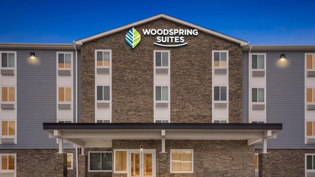 A hotel with a stone facade, a flat roof, and a sign reading "WOODS SPRING SUITES". - Woodspring Suites Wilmington Riverfront (Wilmington)
