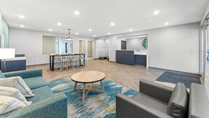 A spacious living area with a sofa, a round coffee table, and a dining area with chairs and a table. - Woodspring Suites Wilmington Riverfront (Wilmington)