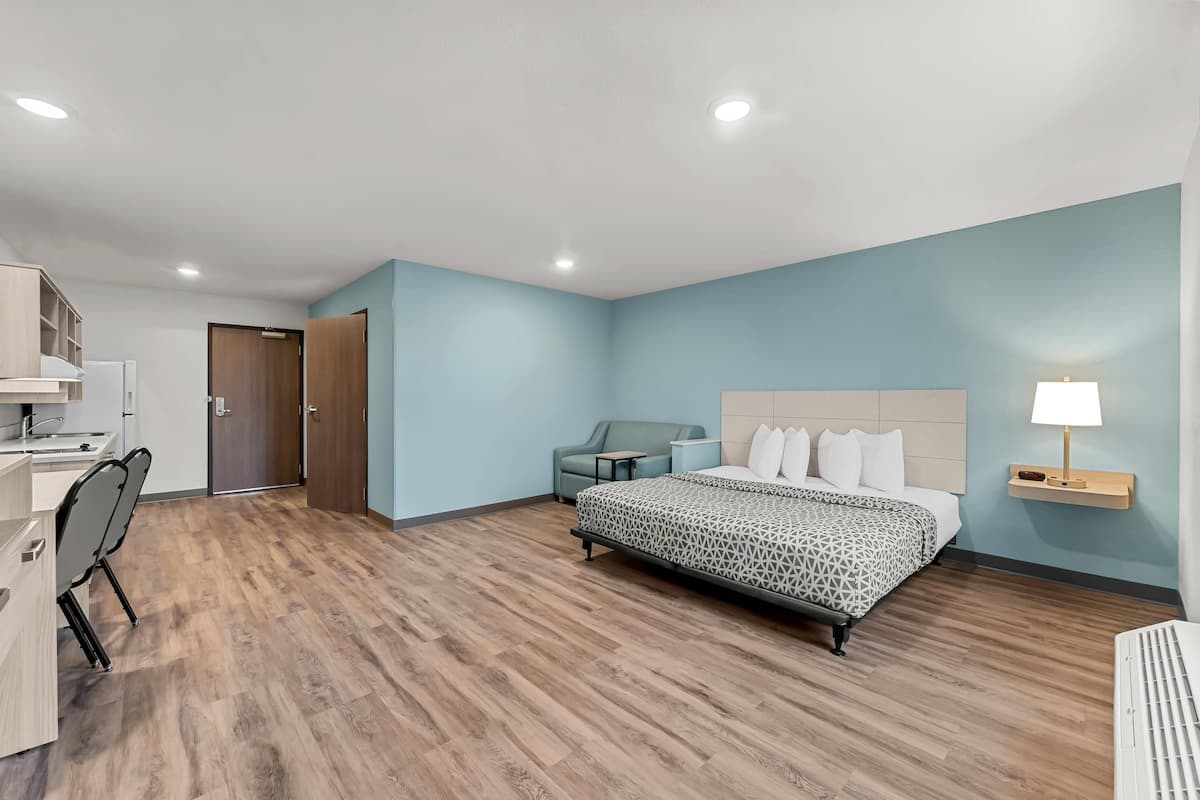 Una habitación de hotel moderna con una cama grande, un escritorio, una silla y un armario.
