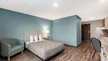 Una habitación de hotel moderna con cama, una silla, un escritorio y una kitchenette.