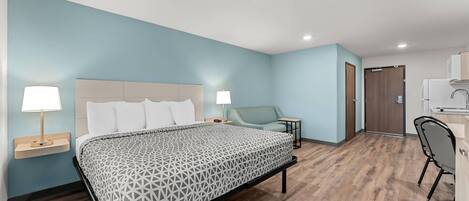 A modern hotel room with a bed, bedside tables, a desk, and a chair.