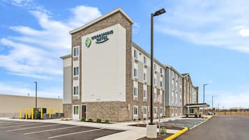 A hotel with a modern design, featuring a prominent logo on the facade, a fire lane sign, and a parking lot.