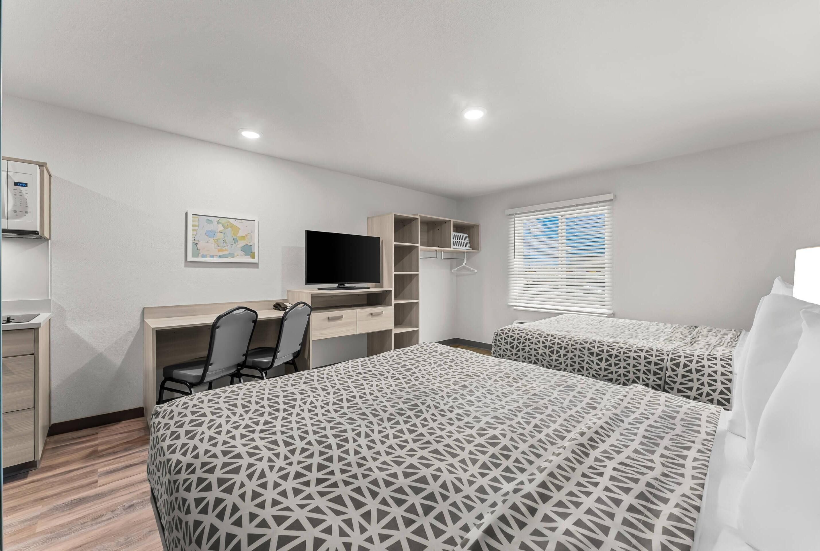 A bedroom with a bed, a desk, a chair, a TV, and a wardrobe.