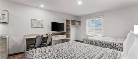 A bedroom with a bed, a desk, a chair, a TV, and a wardrobe.