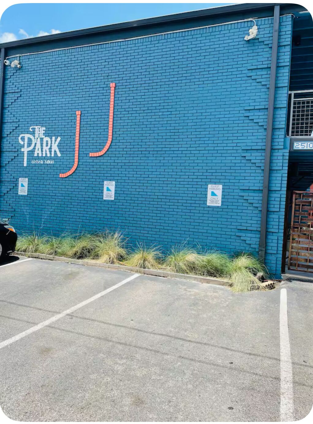 A blue building with a sign reading "The Park Airbnb Hotel" and a parking lot in front.
