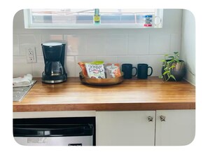 A kitchen with a coffee maker, a bowl of snacks, and a potted plant.