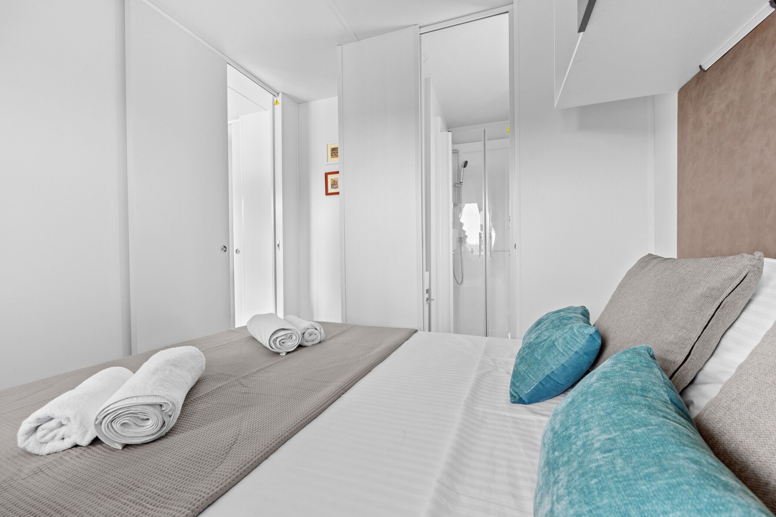 A hotel room with a bed, a bathroom visible through an open door, and a neatly made bed with towels.