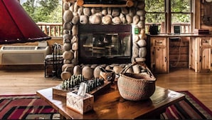 Una chimenea de piedra con un televisor, un tablero de ajedrez y una cesta tejida sobre una mesa de madera.