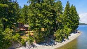 Ein Haus, umgeben von dichtem Wald und einem Strand.