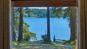 Ein Blick durch ein Fenster auf einen See mit Bäumen und einem Holzzaun.