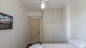 A bedroom with a bed, a bench with a towel, a wardrobe, and a door. - Beachfront Apartment With Side Beach View Ety0024 (Balneário Camboriú)