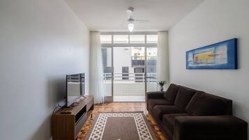 En stue med sofa, TV og loftventilator.