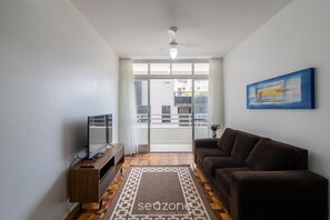 A living room with a sofa, TV, and a ceiling fan. - Apt. w/ Balcony & Sea View 360m Beach Ety0024 (Balneário Camboriú)