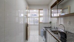 A modern kitchen with white tiles, stainless steel appliances, and a window with a view of the outside. - Apt. w/ Balcony & Sea View 360m Beach Ety0024 (Balneário Camboriú)