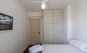 Un dormitorio con una cama, un banco con una toalla, un armario y una puerta.