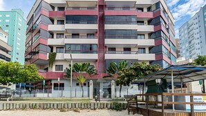 A multi-story building with balconies, a central stairwell, and a covered area with benches. - Apt Foot in the Sand sea View in Meia Praia Evb308 (Itapema)