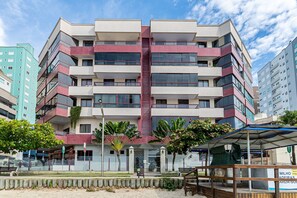 A multi-story building with balconies, a central stairwell, and a covered area with benches. - Apt Foot in the Sand sea View in Meia Praia Evb308 (Itapema)