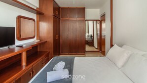 A bedroom with a bed, a wooden wardrobe, a TV on a wooden stand, and a mirror. - 3BR Apt w/ Balcony 100m From Beach Evz0601 (Balneário Camboriú)