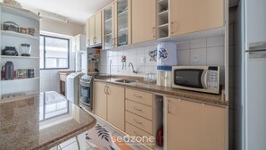 A kitchen with beige cabinets, a microwave, a stove, and a sink. - Apt With sea View and Barbecue in Itapema Gbl601 (Itapema)