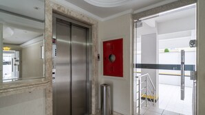 An elevator, a red fire alarm box, and a trash can in a hallway. - Apt With sea View and Barbecue in Itapema Gbl601 (Itapema)