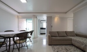 Una sala de estar moderna con un sofá, una mesa de comedor con sillas y una cocina al fondo.