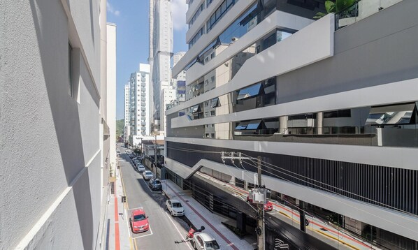 A multi-story building with a modern architectural design, featuring a pedestrian overpass and a busy street below.