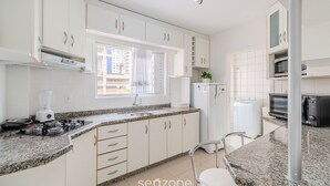Una cocina moderna con armarios blancos, encimera de granito, cocina a gas, horno empotrado y microondas.