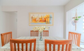 A dining area with a table set for four, wooden chairs, a lace tablecloth, a vase with flowers, and a painting on the wall. - 3 Bedroom apt 300m fr the Central Beach BC Idn0402 (Balneário Camboriú)