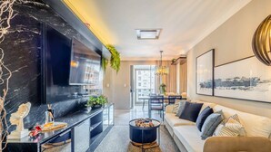 A modern living room with a large flat-screen TV, a round coffee table, and a sofa. - Modern and Fully Equipped Apartments Just Minutes From the sea at Meia Praia - GRI (Itapema)