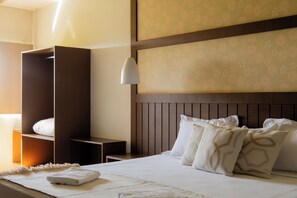 Ein Hotelzimmer mit Bett, Nachttisch, Kleiderschrank und einem Kopfteil mit floralem Muster.
