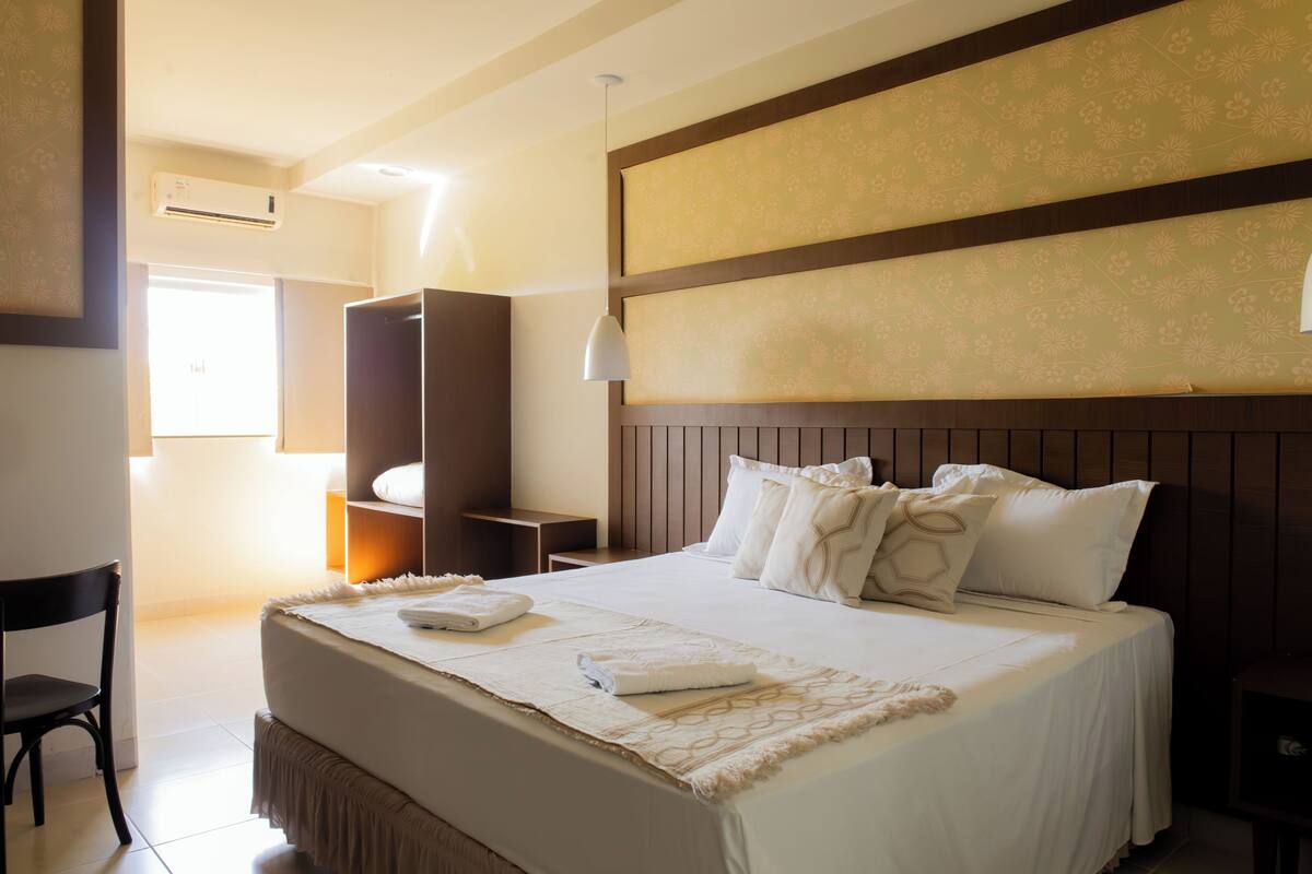 Una habitación de hotel con una cama grande, un armario, un escritorio y una silla.