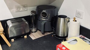A kitchen with a toaster, coffee maker, kettle, and a box of baby products. - New house ground floor 2 bedrooms garage terrace (La Tour-du-Crieu)