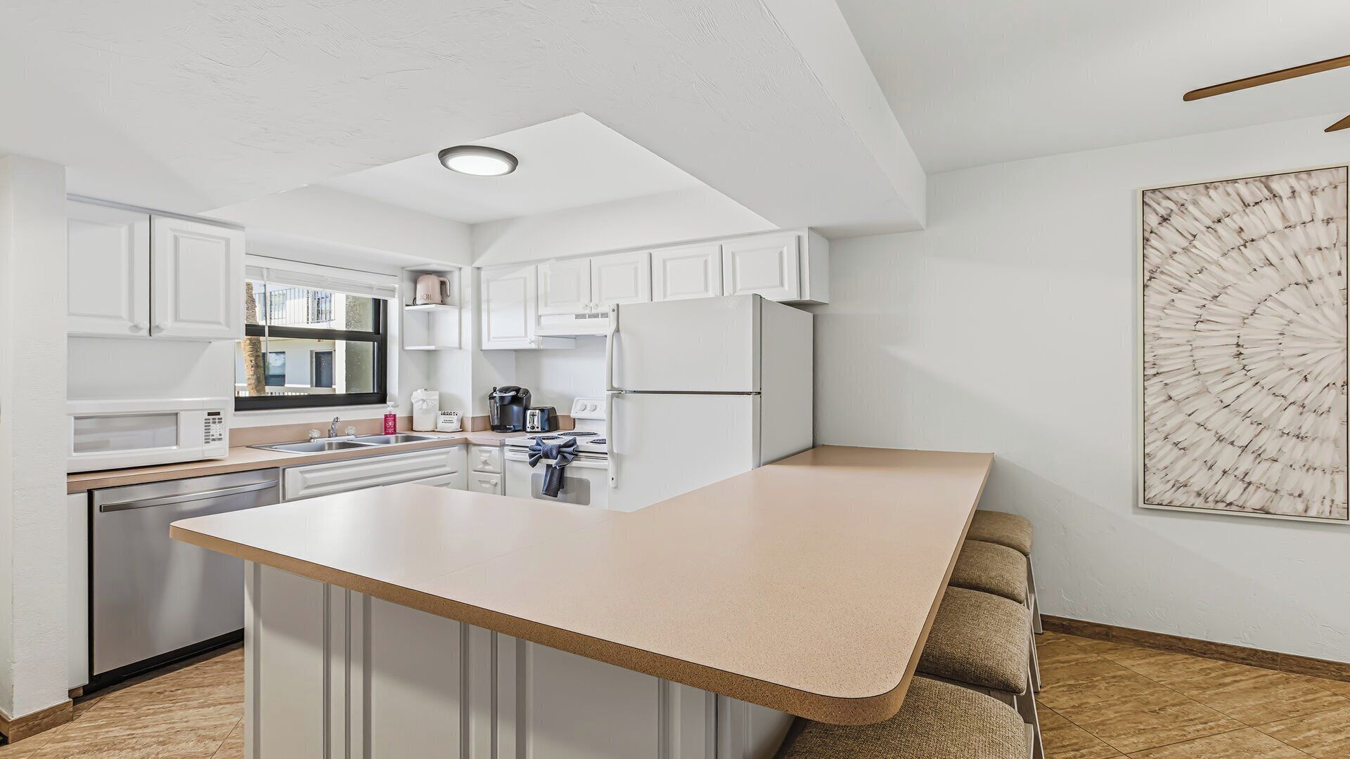 A modern kitchen with white cabinetry, a central island, and a large window.
