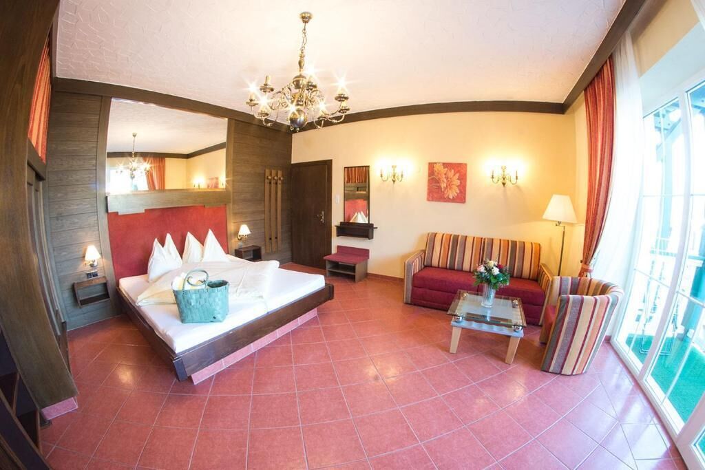A hotel room with a bed, a sofa, a coffee table, and a chandelier.