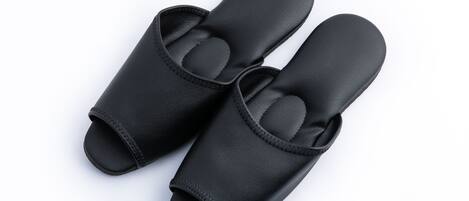 Un par de zapatos negros de vestir sin cordones, con suela texturizada y una tira en la parte superior.