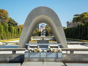 Ett monument av sten med inskriptioner och blomsterkransar i en vacker park.
