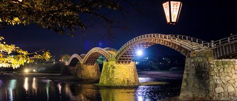 Eine Steinsche Brücke über Wasser bei Nacht mit beleuchteten Schildern.