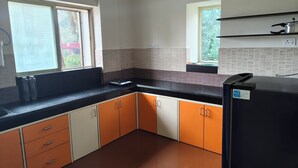Una cocina con armarios naranja y blanco, encimera negra y refrigerador negro.