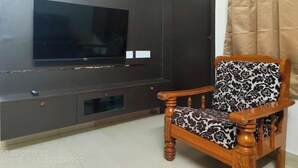 Una sala de estar con un mueble multimedia oscuro, un televisor de pantalla plana y un sillón estampado.