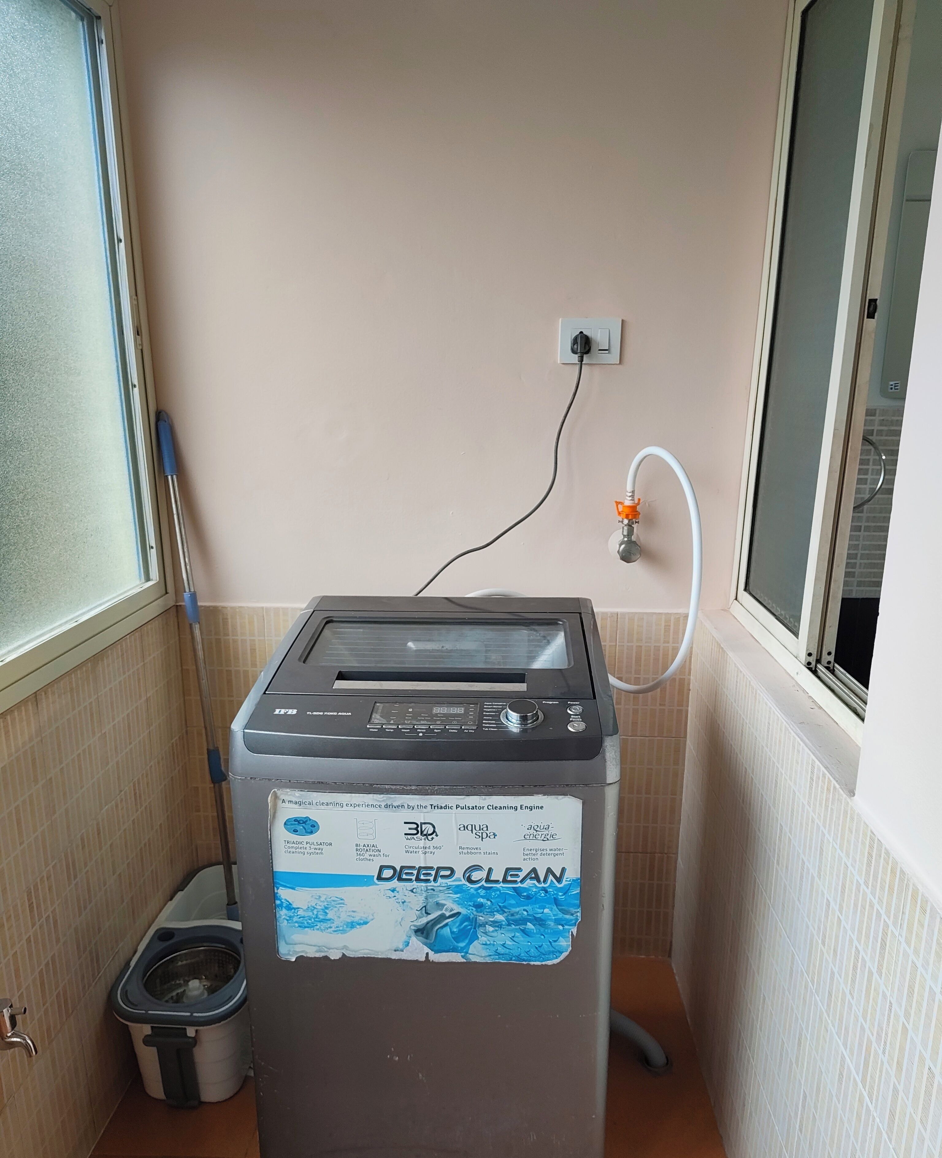 Eine kompakte, an der Wand montierte Waschmaschine mit Bedienfeld und Wasseranschluss.