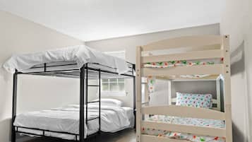 A bunk bed with a white canopy and a lower bunk with a colorful floral bedspread.