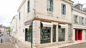 A building with a storefront labeled "L'ENFLE DE PIERRES" and a red door to the right.