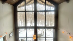 Una habitación con un amplio ventanal que da a una terraza nevada.