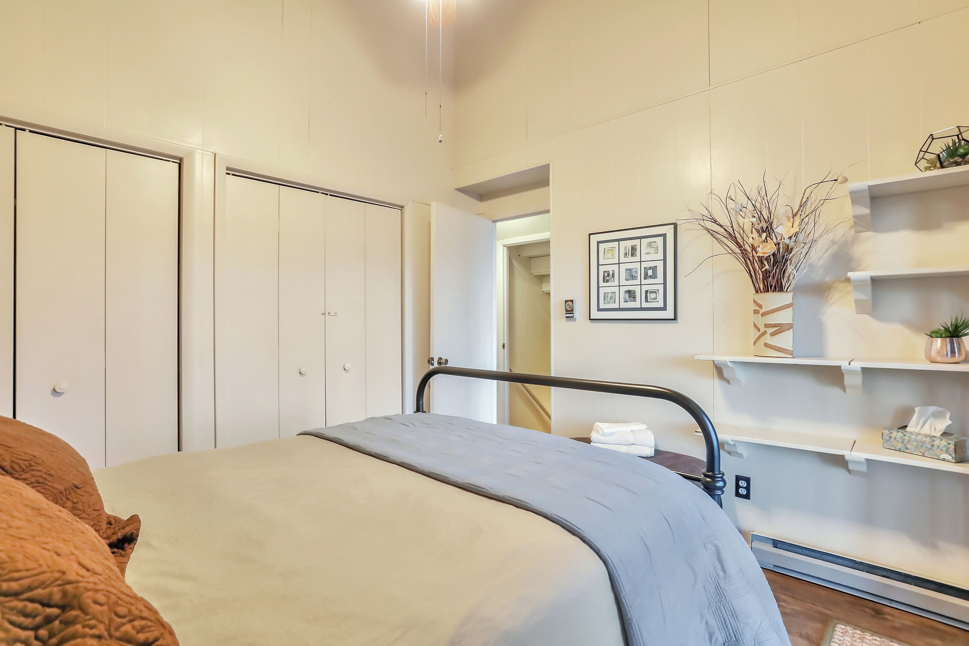 Une chambre à coucher comprenant un lit, une armoire, une étagère avec des objets décoratifs et un tableau encadré accroché au mur.