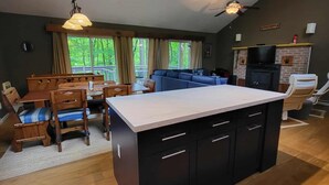 Une cuisine spacieuse avec un îlot central, un coin repas avec des chaises, un canapé et une cheminée.