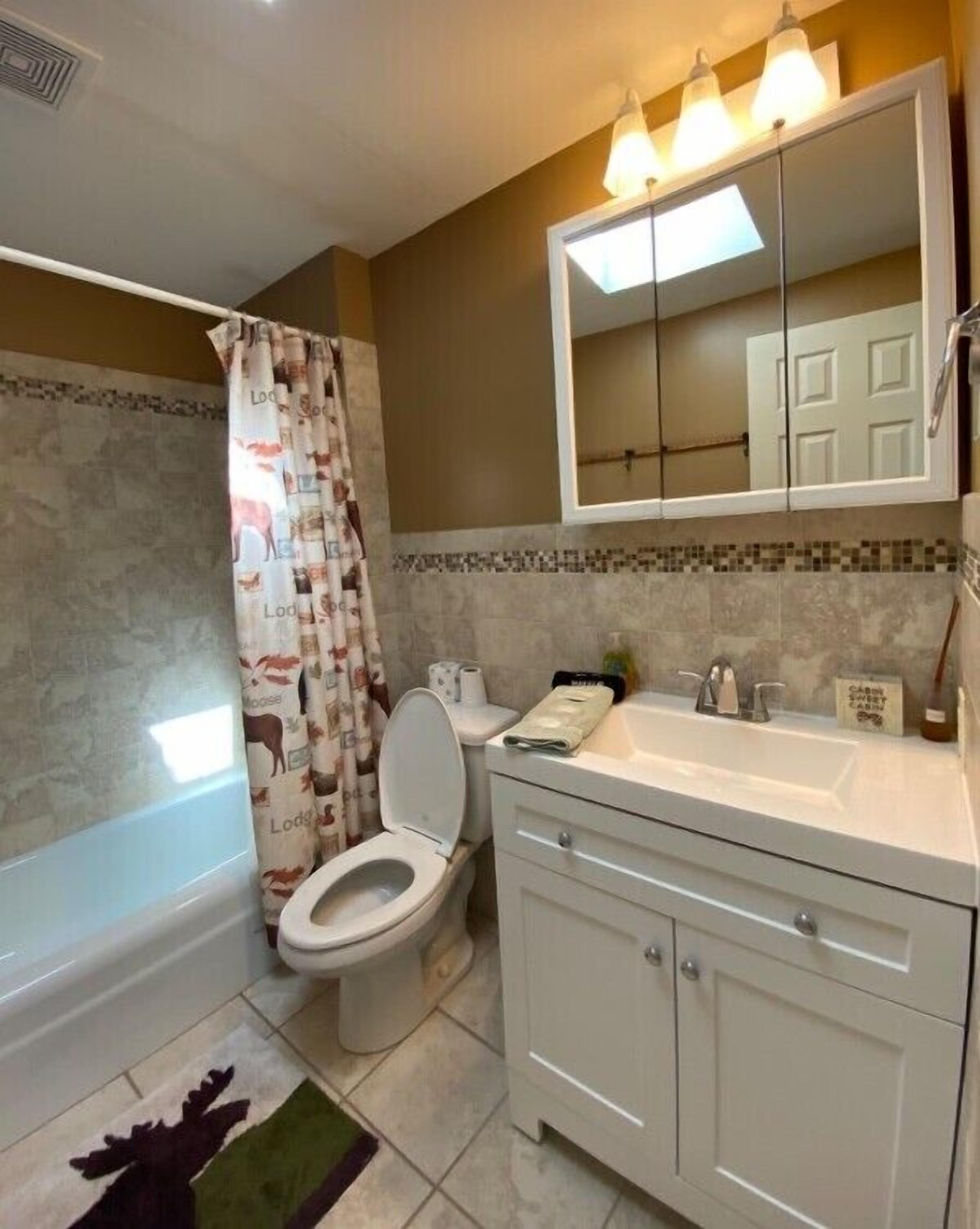 A bathroom with a toilet, sink, mirror, and shower curtain.