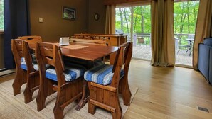 Un coin repas avec une table et des chaises en bois, un luminaire suspendu et une vue sur l’extérieur.